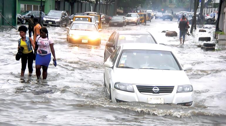 A sedan car partially submerged in water on a flooded road in Surulere during a Lagos downpour.