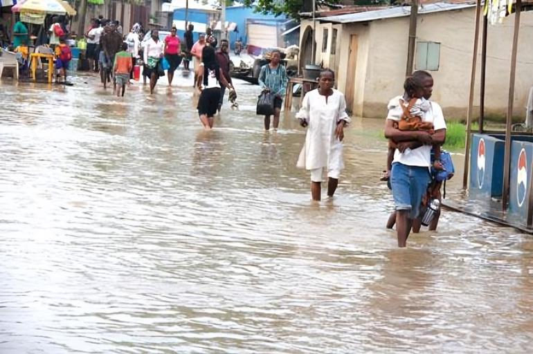 Residents walking through deep floodwaters in Ajegunle Lagos community.