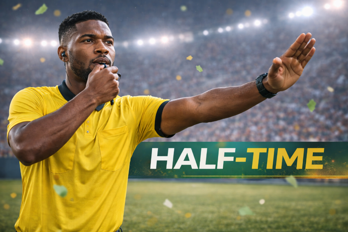 A football referee signals halftime in the match