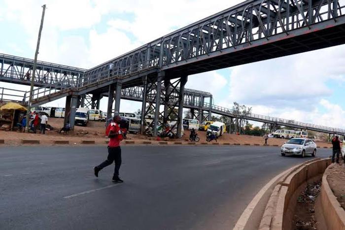 A person crossing the road instead of using a footbridge