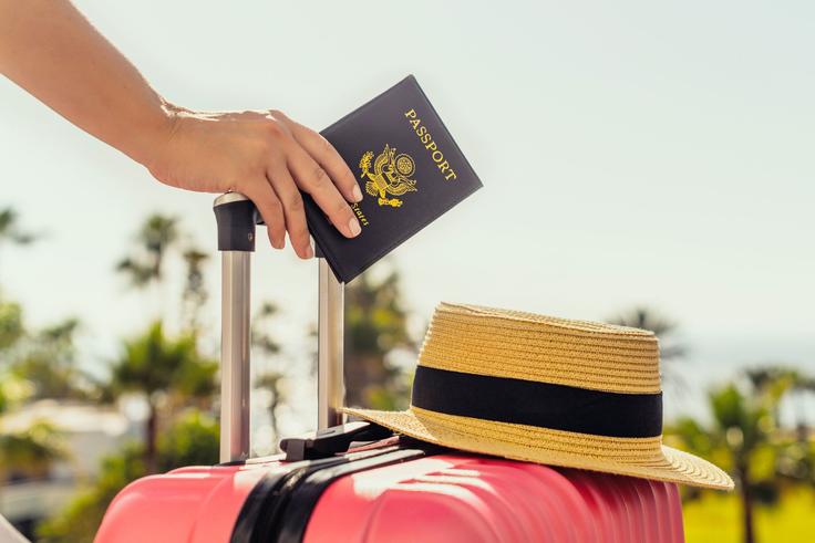 A person holding a suitcase and U.S. passport