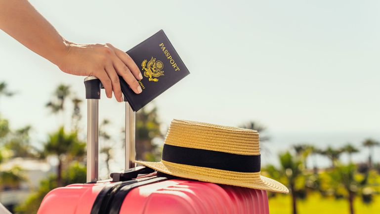 A person holding a suitcase and U.S. passport