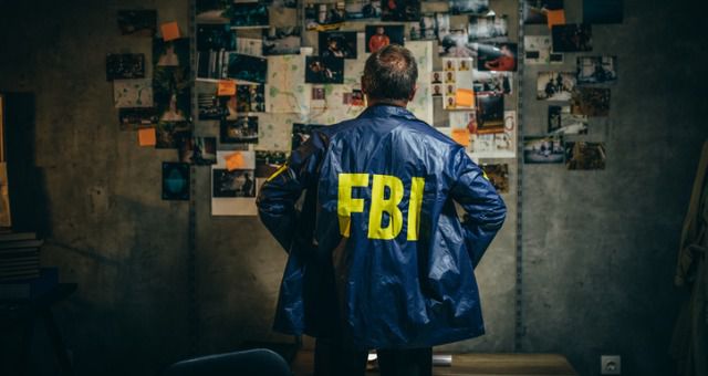 An FBI officer looking at pictures on a notice board trying to solve a crime