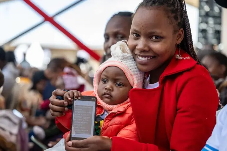 A young mother and her child shows off a message from the Nyota Fund program during a recent activation drive (Image: Files)