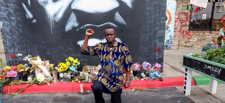 PLO Lumumba kneels to pay respects during a visit in July 2021 to the site where George Floyd was killed by a Minneapolis Police Officer Derek Chauvin (Image: Files)