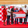 Kenya Airways, Chief Commercial and Customer Officer, Julius Thairu hands over the partnership cheque to the KOGL board members