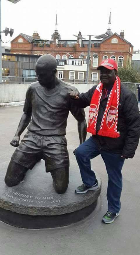 The late former Prime Minister of the Republic of Kenya, Raila Amolo Odinga, poses alongside a statue of Arsenal Legend Thierry Henry at the Emirates Stadium in London
