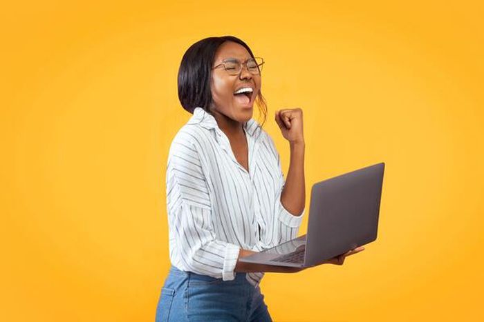 A person showing excitement while holding a laptop