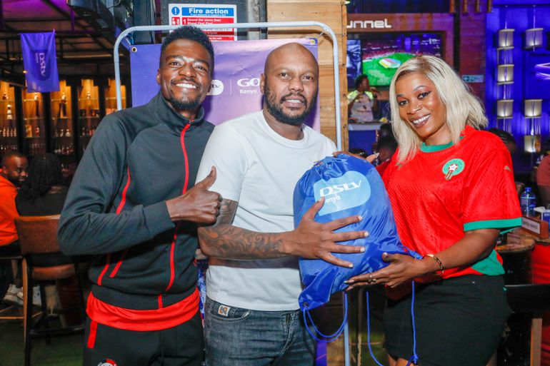 Influencer Usefulidioty (Left), with Judith Adhiambo (Right) a brand ambassador presents a gift pack to a Kahoot winner, Alfred Macharia(Centre) during the AFCON launch and watch party held at The Tunnel courtesy of MultiChoice Kenya and Visionplus