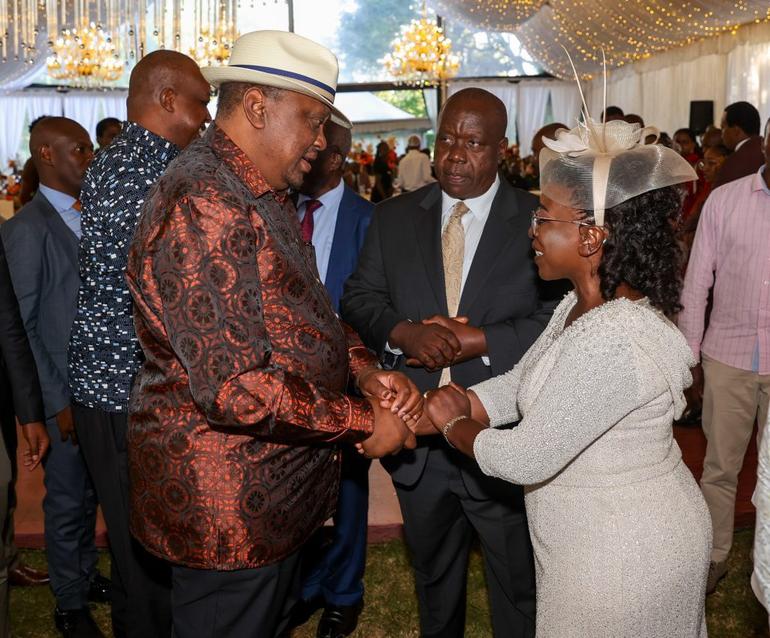 Former Interior CS Fred Matiang'i (in suit) looks on as his wife shakes hands with former President Uhuru Kenyatta at the wedding of his daughter, Wendy