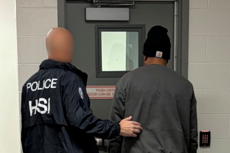 Homeland Security Investigations (HSI) agent arresting a suspect on charges of alleged false statements related to voter registration and visa fraud