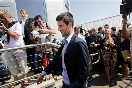 Djokovic disfruta la vista desde el  Empire State al lado de su trofeo. FOTO: AP