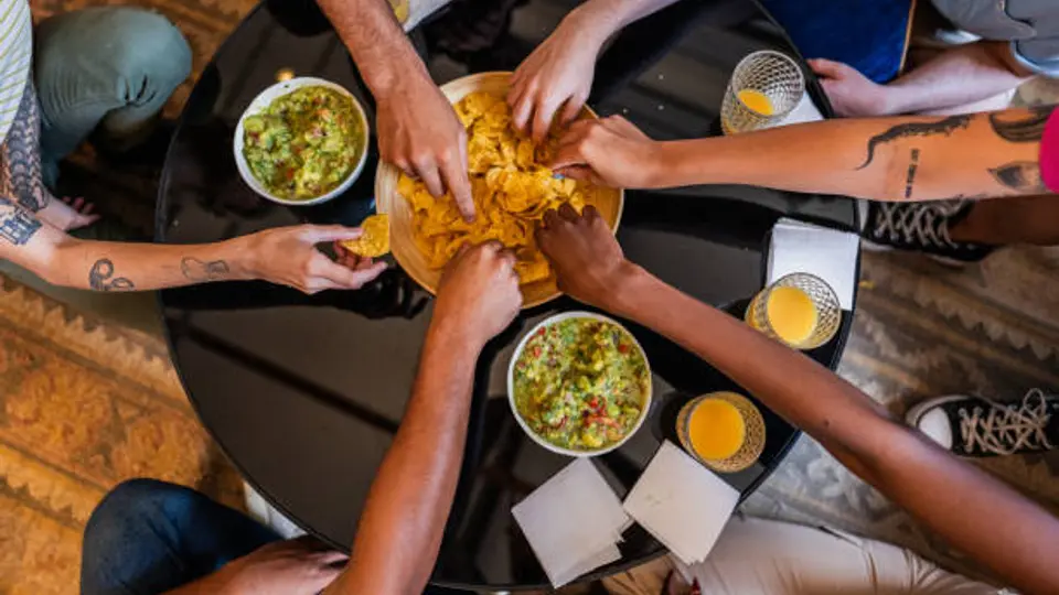 Familias y amigos comparten botanas como guacamole mientras ven el partido. / iStock