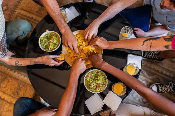 Familias y amigos comparten botanas como guacamole mientras ven el partido. / iStock