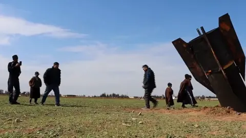 Tras la caída del proyectil, los habitantes se acercan para inspeccionar y tomarse fotos. / AP