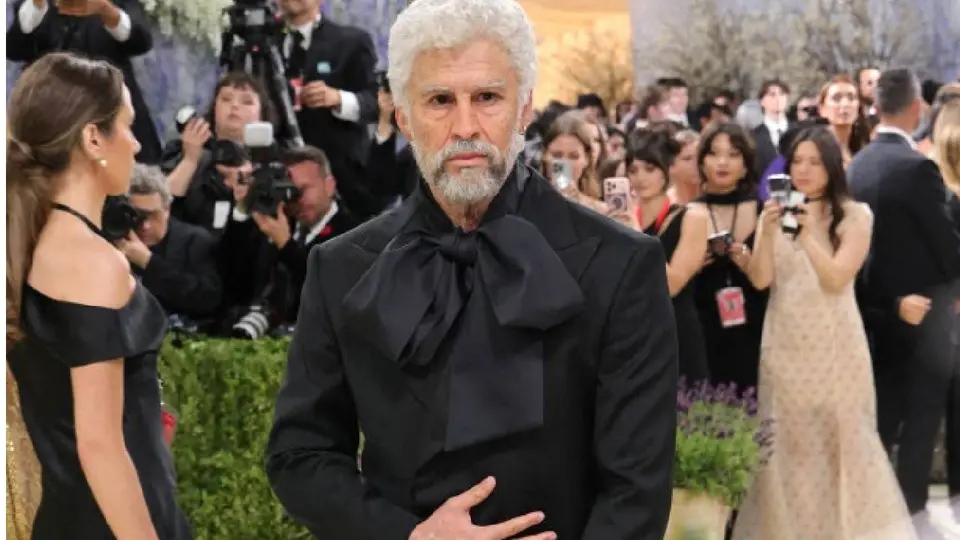 El artista combinó su look con un traje negro y moño oversized en la alfombra roja./ AFP