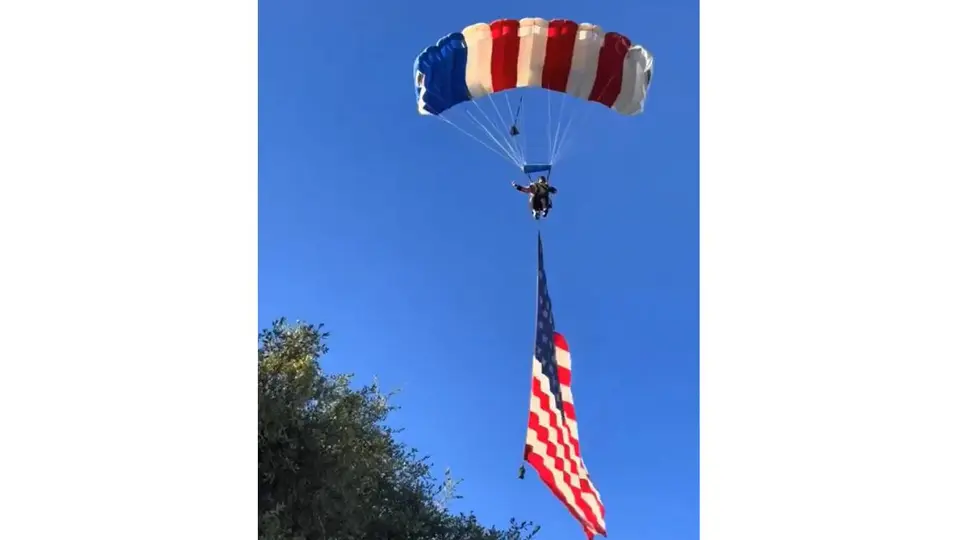 El paracaidista descendía con una bandera de Estados Unidos durante una exhibición aérea por el 4 de julio. / RS