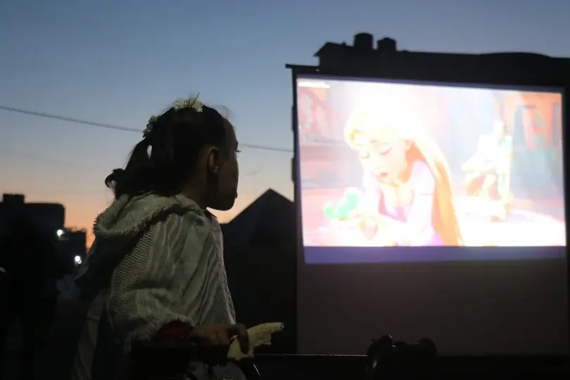 La pantalla fue instalada en un espacio rodeado por las huellas de la guerra, donde decenas de niños pudieron disfrutar de un momento de entretenimiento./ masharawifilms.org