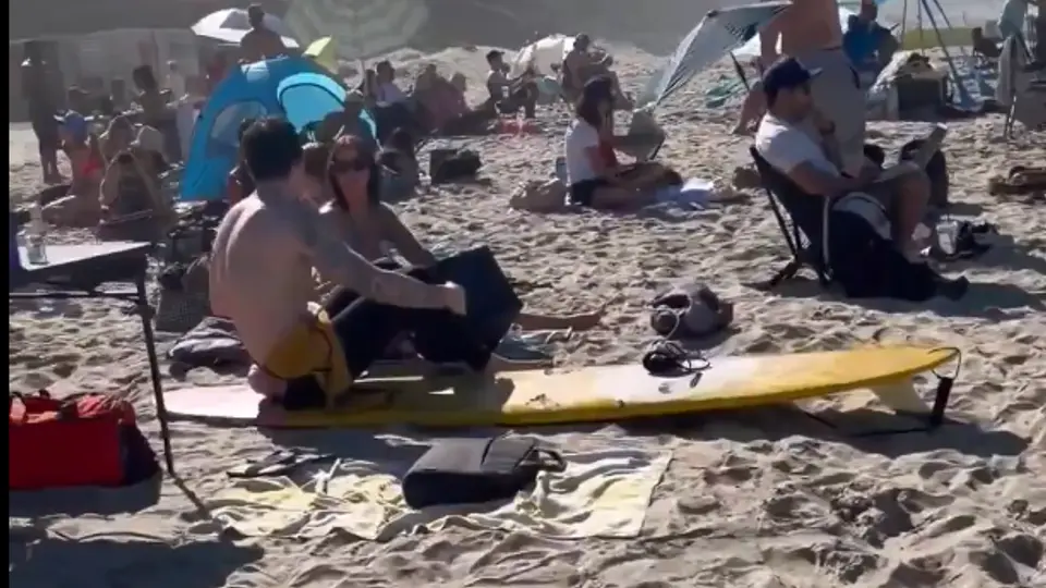 Trabajadores remotos instalaron laptops y escritorios improvisados en la arena de Pacific Beach. / X