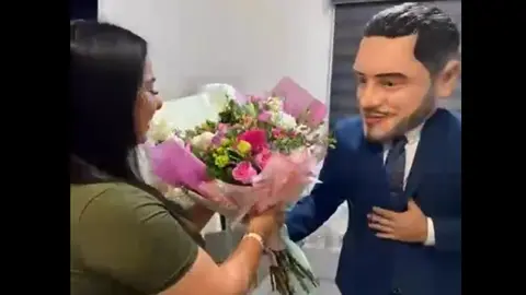 Una botarga con la imagen de Harfuch entregando flores. / RS