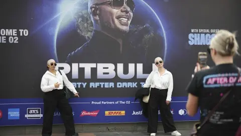 Fans posando caracterizadas de Pitbull. / AP