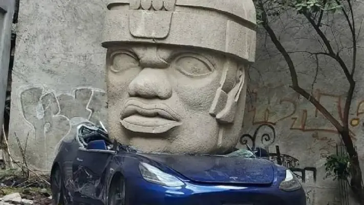 En CDMX aparece Tesla aplastado por una cabeza Olmeca