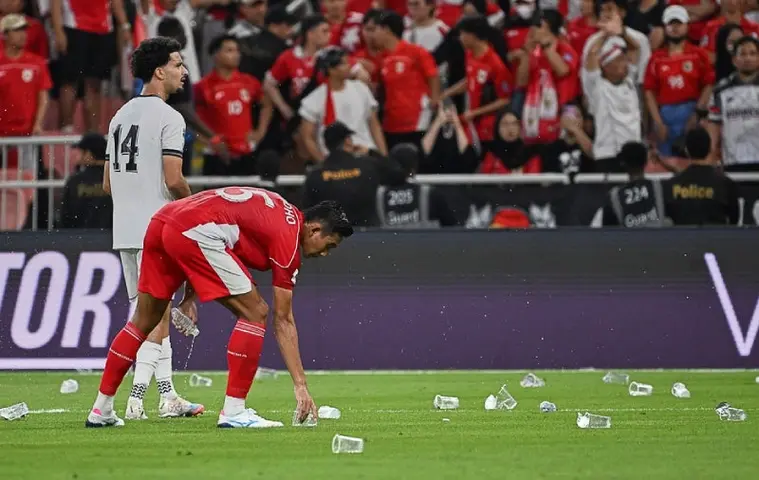 Rizky Ridho levanta vasos de plástico arrojados a la cancha, en el Irak vs Indonesia I AP