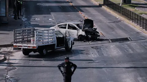 Un policía observa un vehículo incendiado en la carretera de Guadalajara tras el operativo | AP