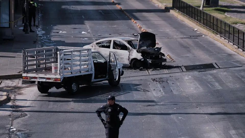 Un policía observa un vehículo incendiado en la carretera de Guadalajara tras el operativo | AP