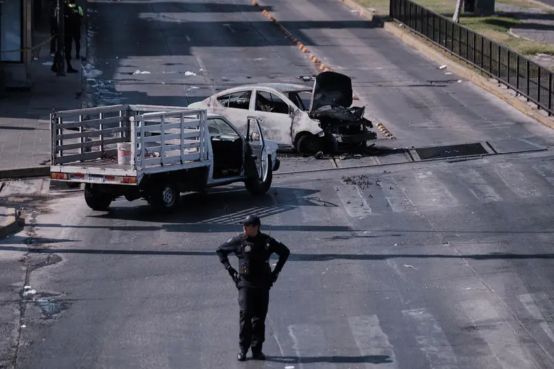Un policía observa un vehículo incendiado en la carretera de Guadalajara tras el operativo | AP