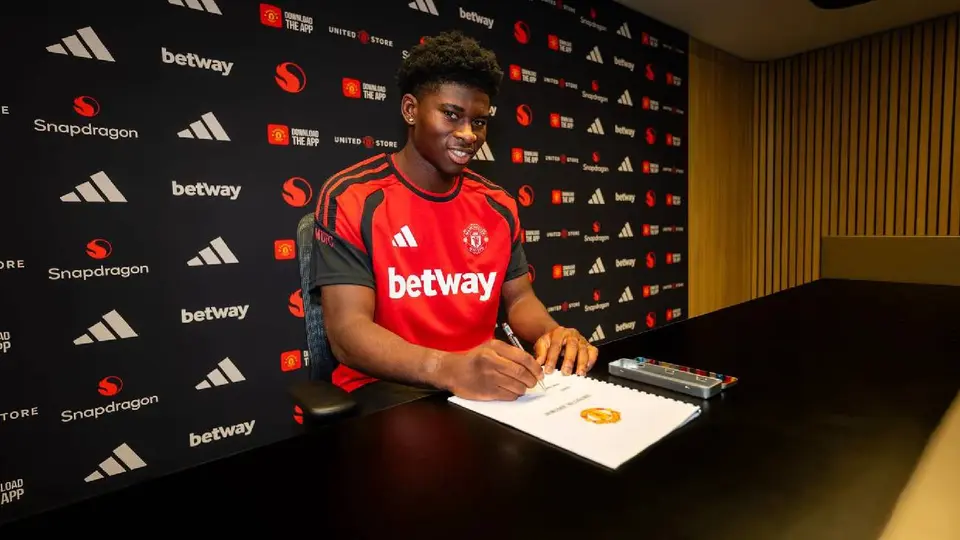 Carlos Baleba, firmando contrato con el Manchester United / X @ManUtd