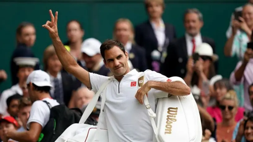 Padre de Roger Federer le ayuda a firmar autógrafos