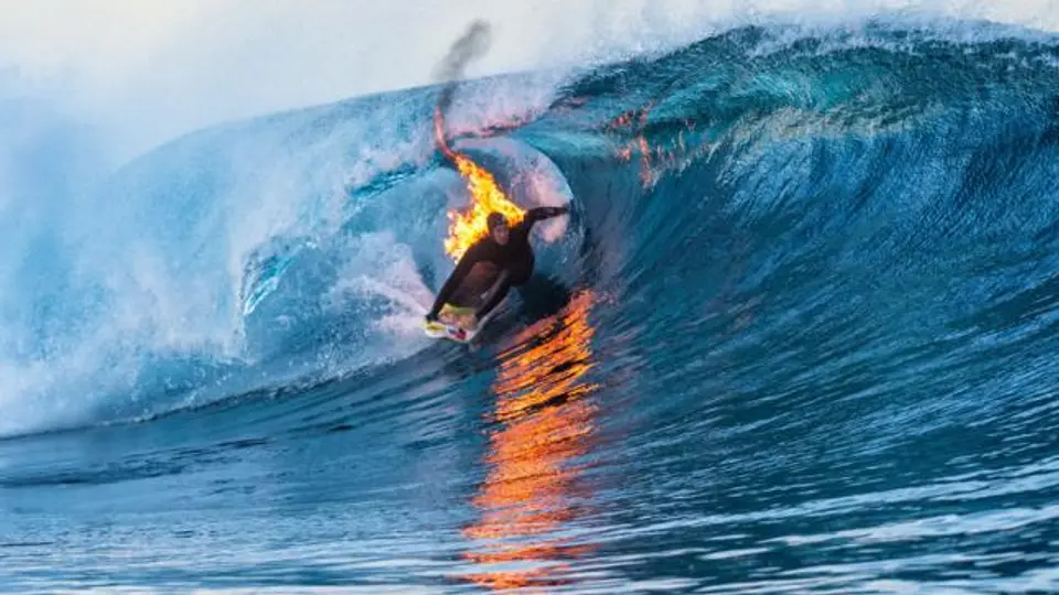 Surfista domina las olas envuelto en llamas