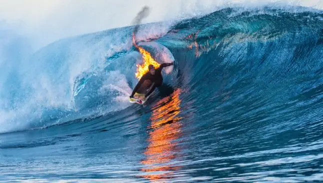 Surfista domina las olas envuelto en llamas
