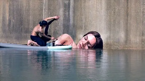 Artista pinta murales sobre una tabla de surf