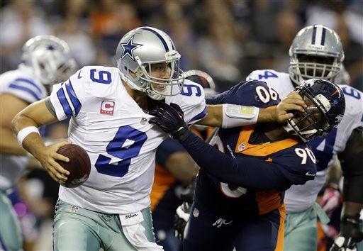 Tony Romo, pasador de los Vaqueros intenta liberarse de una captura por parte de Shaun Phillips | AP
