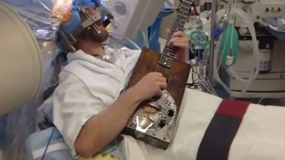 Hombre toca la guitarra mientras lo operan de la cabeza