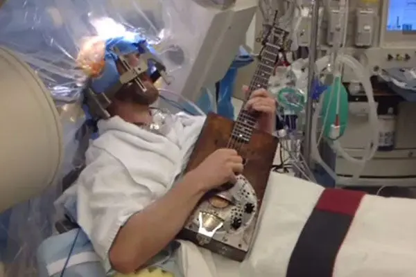 Hombre toca la guitarra mientras lo operan de la cabeza