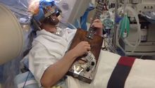 Hombre toca la guitarra mientras lo operan de la cabeza