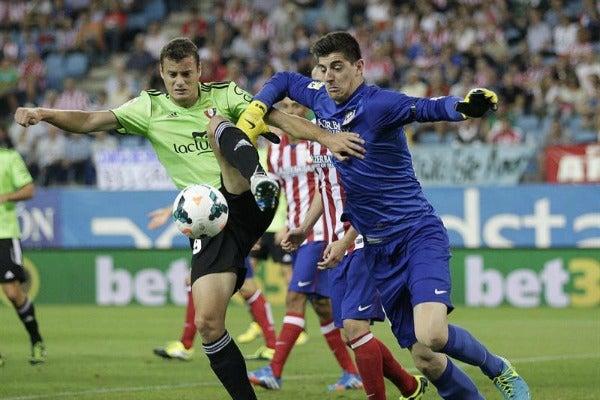 El portero de los Colchoneros, Thibaut Courtois y Oriol Riera del Osasuna disputan el balón | EFE