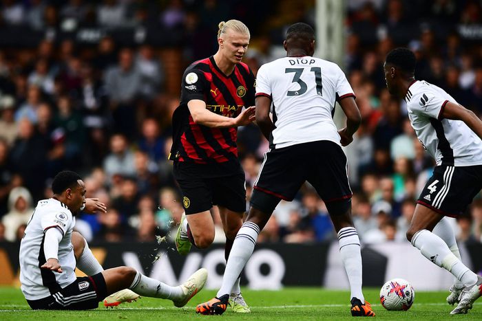 Manchester City's Erling Haaland is challenged by Fulham's players.
