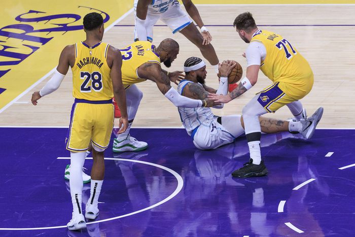 Miles Bridges 0 of the Charlotte Hornets battles for a lose ball with LeBron James 23 and Luka Doncic 77 of the Los Angeles Lakers