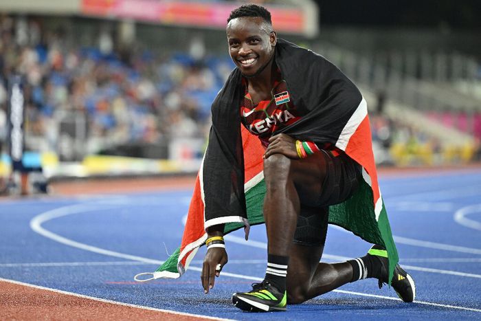 Ferdinand Omanyala celebrating with the Kenyan flag on his back.
