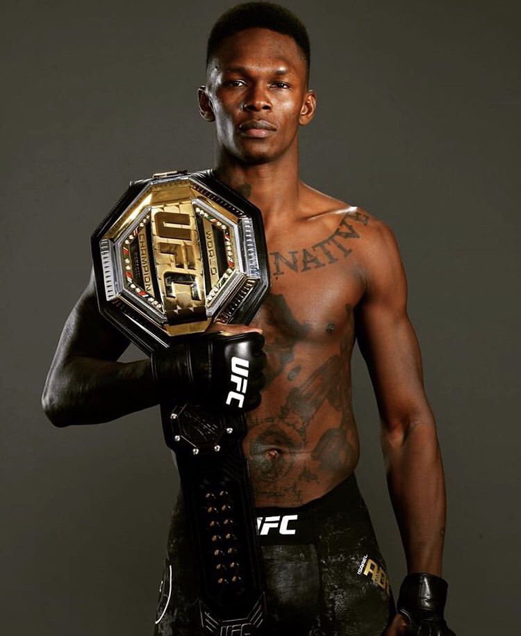 Israel Adesanya posing with his UFC title