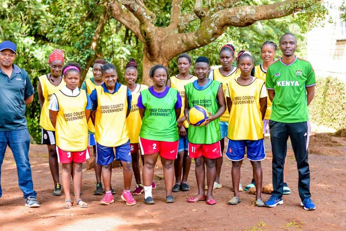 Meru County Chief Officer of Sports, Talent Development and Creative Arts Pithon Muchoki poses with a photo with KYISA Volleyball girls at a training camp.