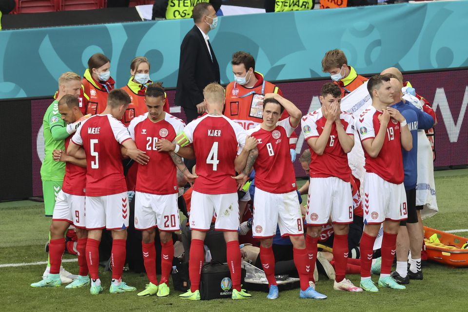 Dánski futbalisti stoja okolo svojho spoluhráča Christiana Eriksena, ktorého záchranári oživujú po tom, čo skolaboval počas zápasu základnej B-skupiny Dánsko - Fínsko