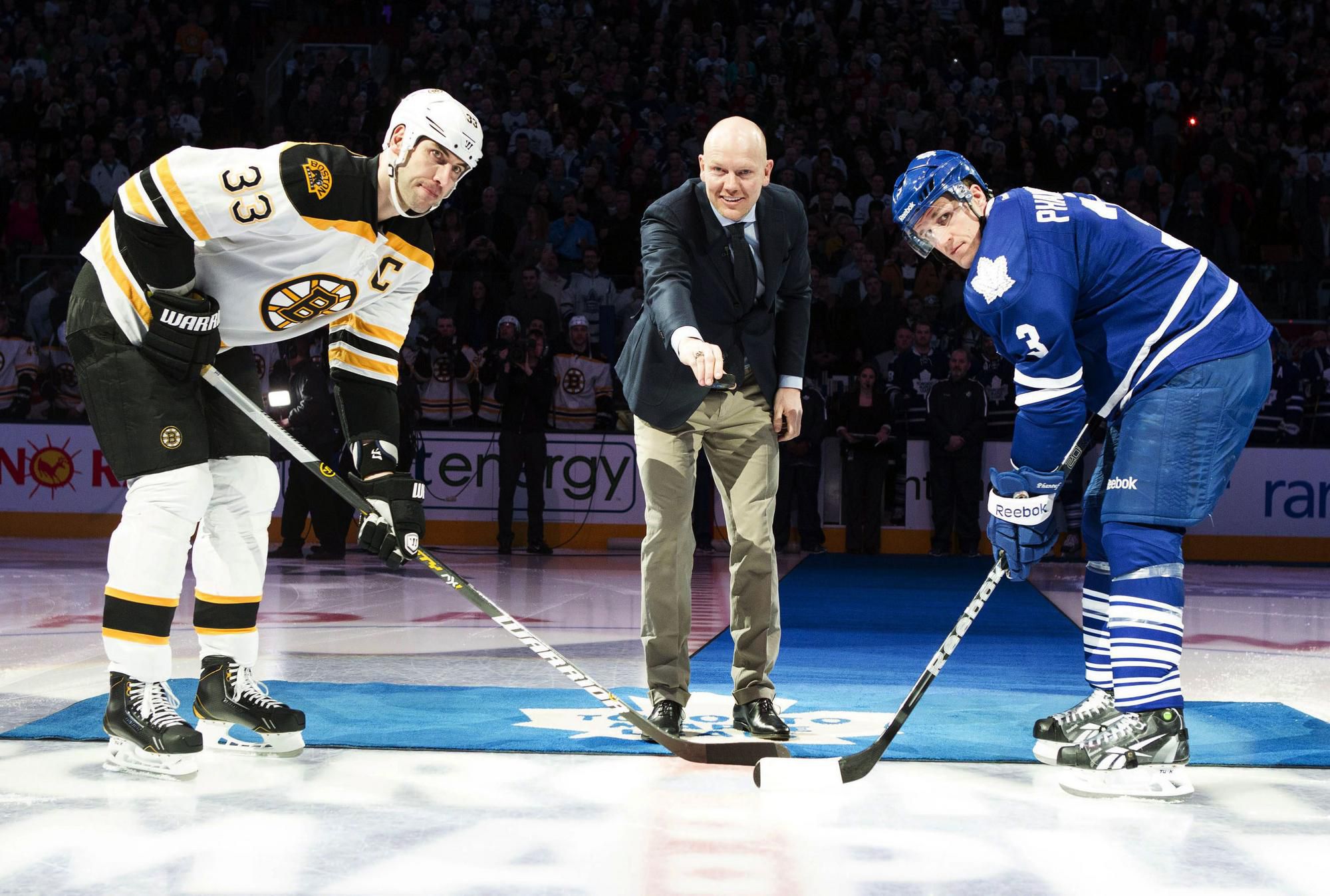 Mats Sundin (uprostred) vhadzuje puk pred začiatkom zápasu zámorskej hokejovej NHL Toronto Maple Leafs - Boston Bruins. Vľavo kapitán Bostonu Slovák Zdeno Chára, vpravo hráč Toronta Dion Phaneuf