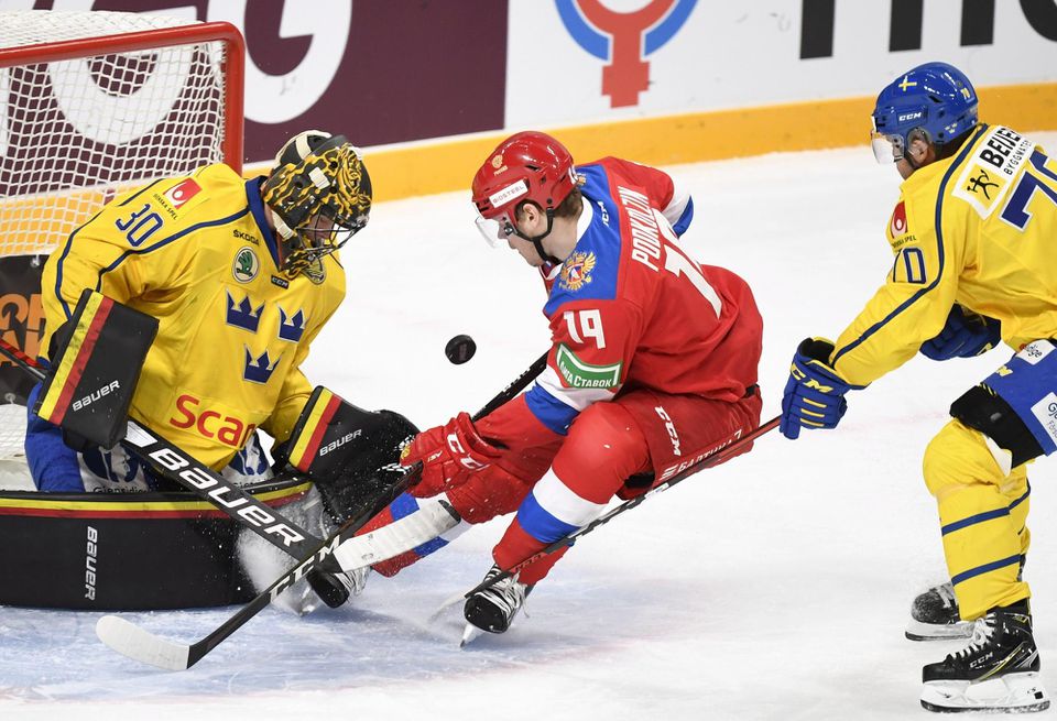 Švédsky brankár Samuel Ersson a ruský hokejista Vasilij Podkolzin v súboji o puk.