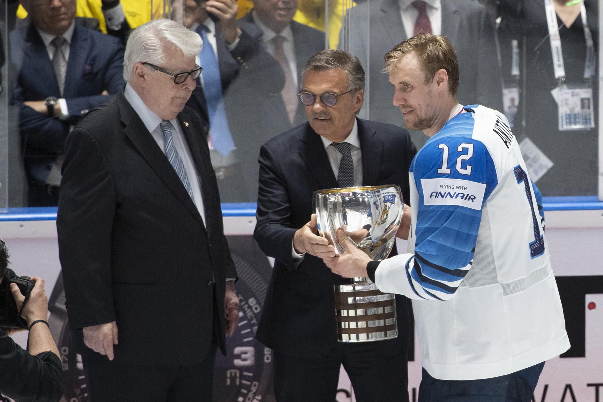 zľava viceprezident IIHF Kalervo Kummola, prezident IIHF René Fasel a Marko Anttila pri preberaní pohára pre víťaza MS 2019