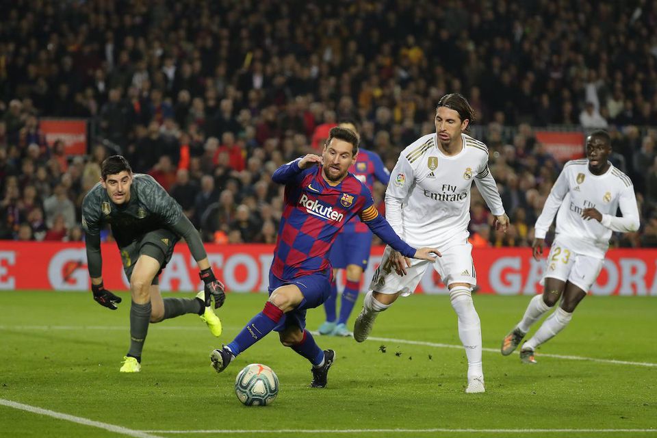 Hráč FC Barcelony Lionel Messi (uprostred) a hráči Realu Madrid zľava brankár Thibaut Courtois  a Sergio Ramos.